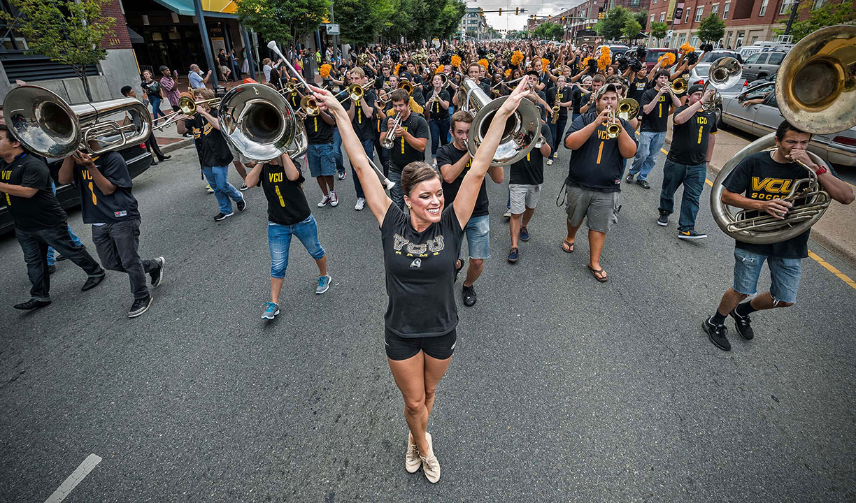 The VCU pep band leads a parade down the street