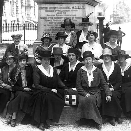 Historical photo of group of female social work students posing in front of statue