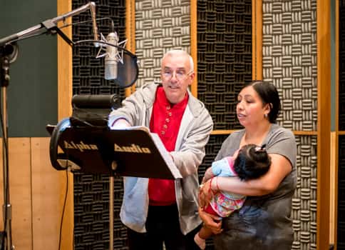 Woman holding baby in recording studio while talking to man