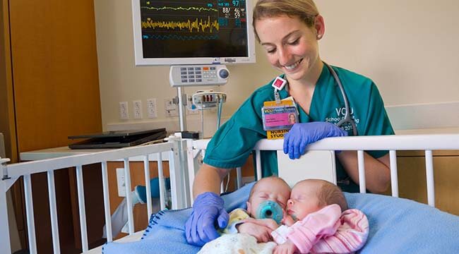 Nurse comforting twin infants in a crib
