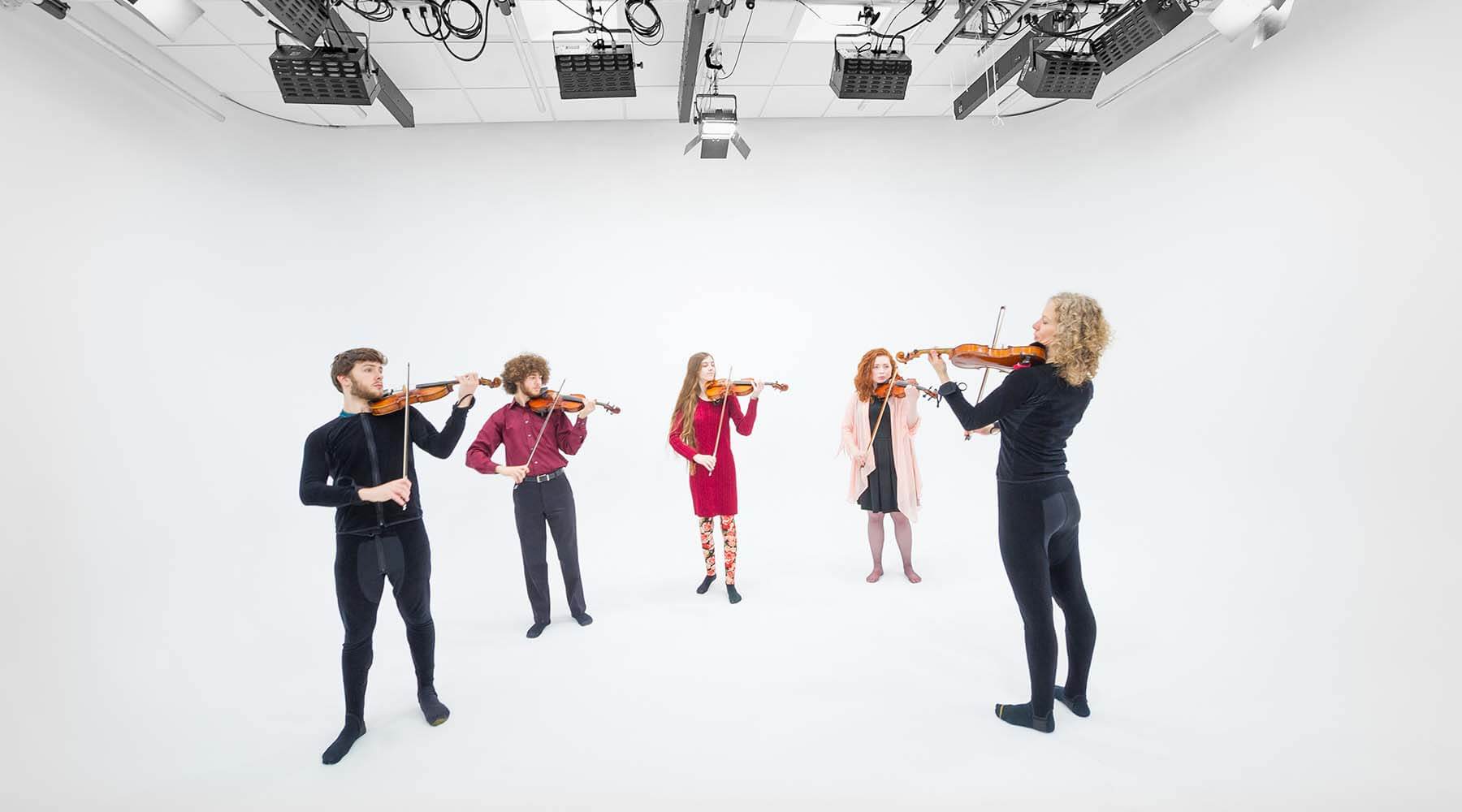Five people playing violin in motion capture lab