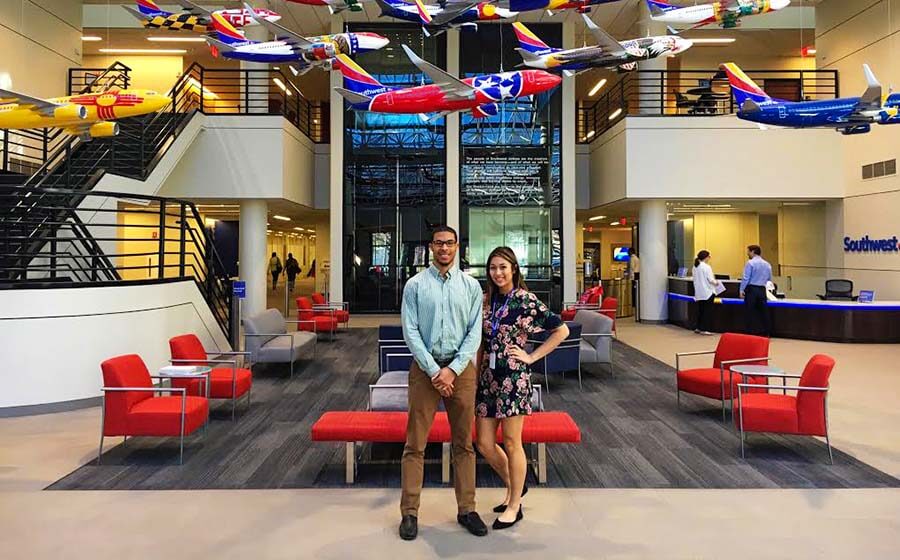 Man and woman standing in colorful lobby with model airplanes hanging overhead