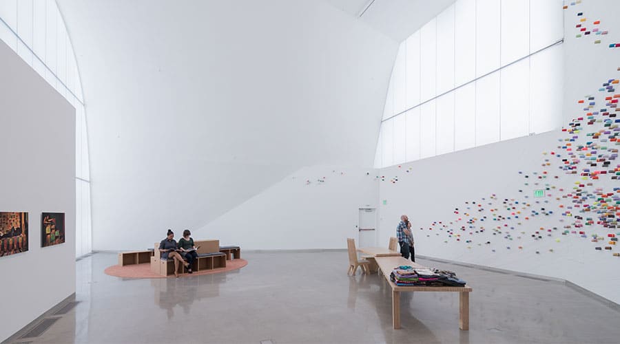 Gallery space inside the Institute for Contemporary Art showing bright-colored spools of thread attached to the walls