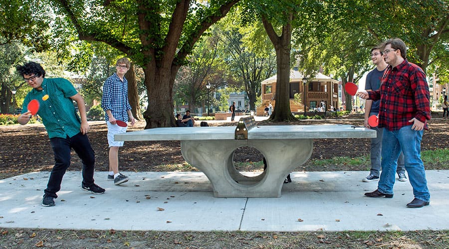Four VCU students play pingpong in the park